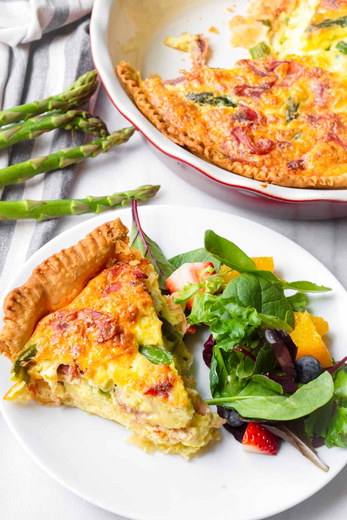 a slice of baked quiche served with a side salad