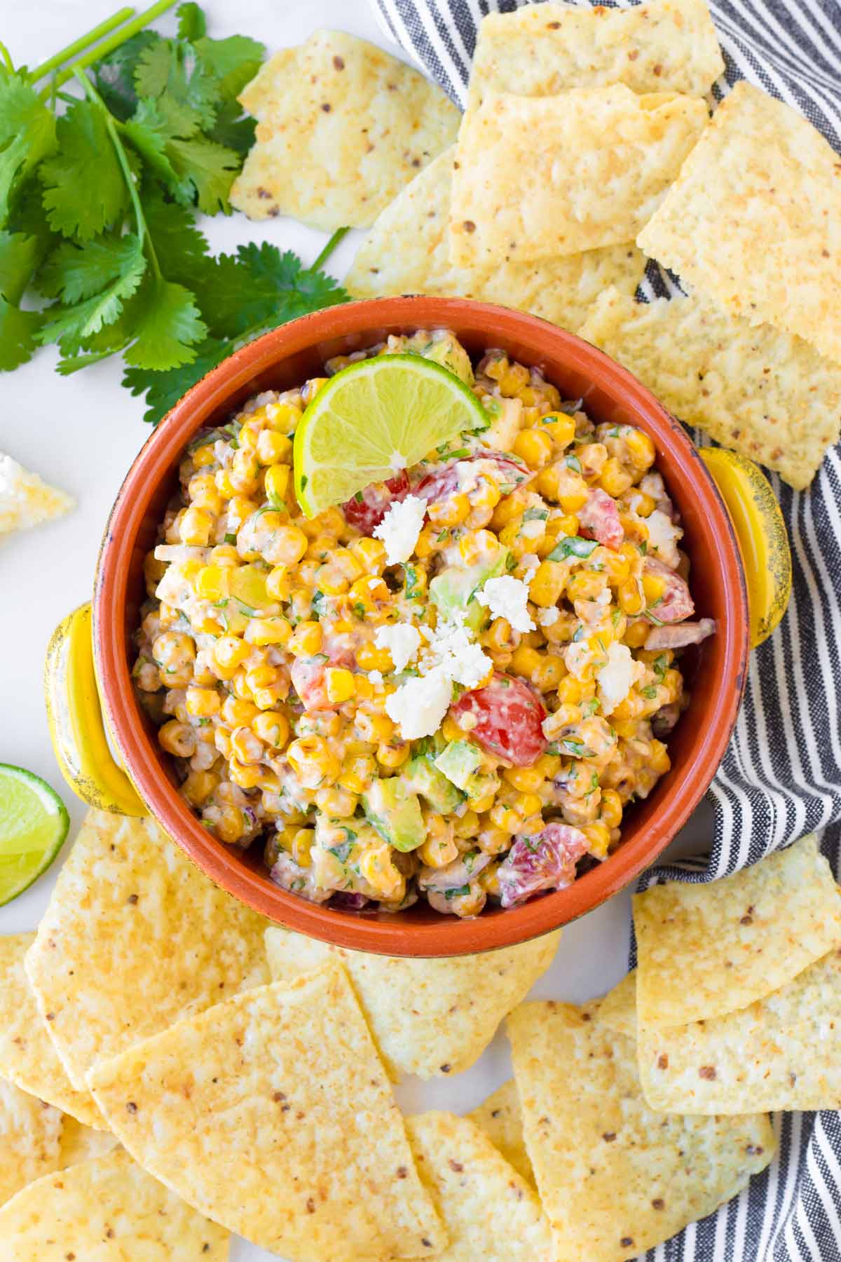 creamy corn salad in an orange bowl with tortilla chips