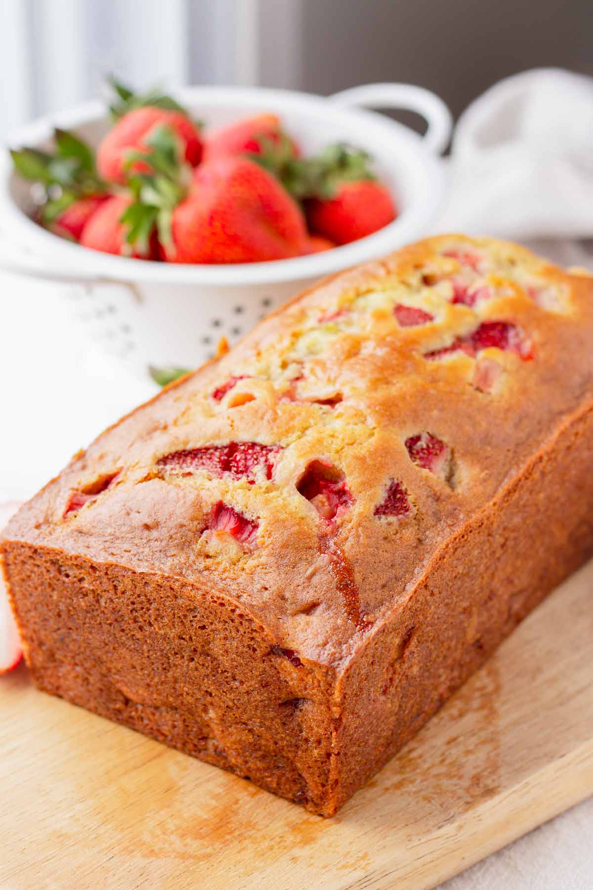 quick bread made with fresh strawberries on a wooden serving board