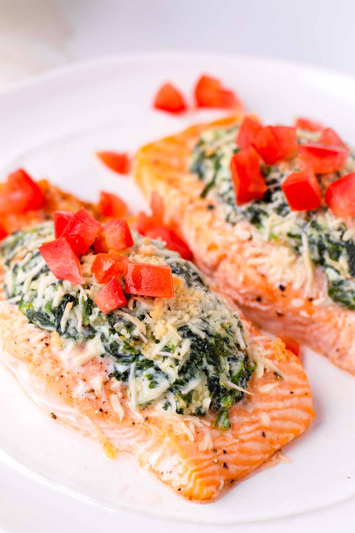 side view of baked salmon florentine topped with diced tomatoes
