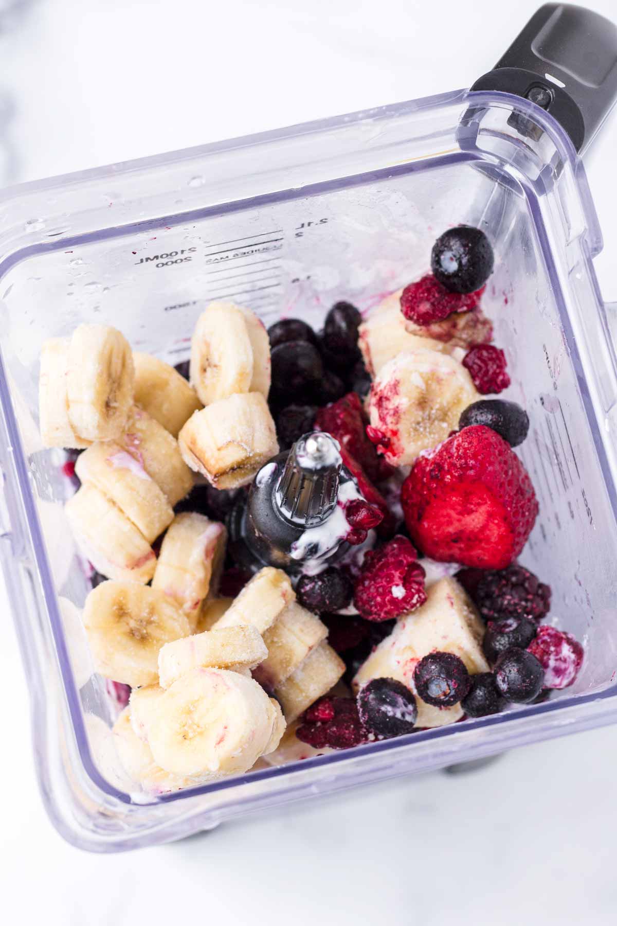 diced bananas, berries, milk, and yogurt inside a blender
