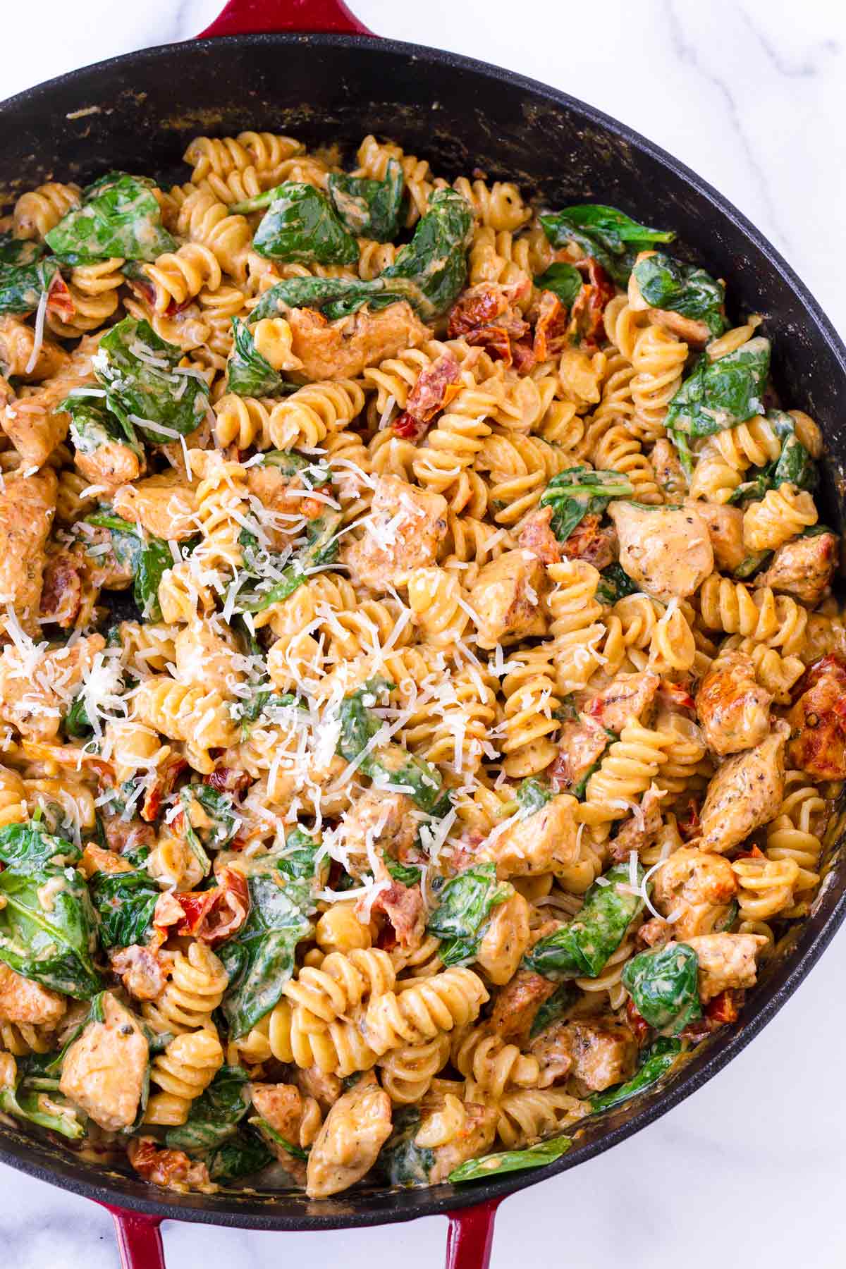 garnished tuscan chicken pasta with creamy sauce on skillet