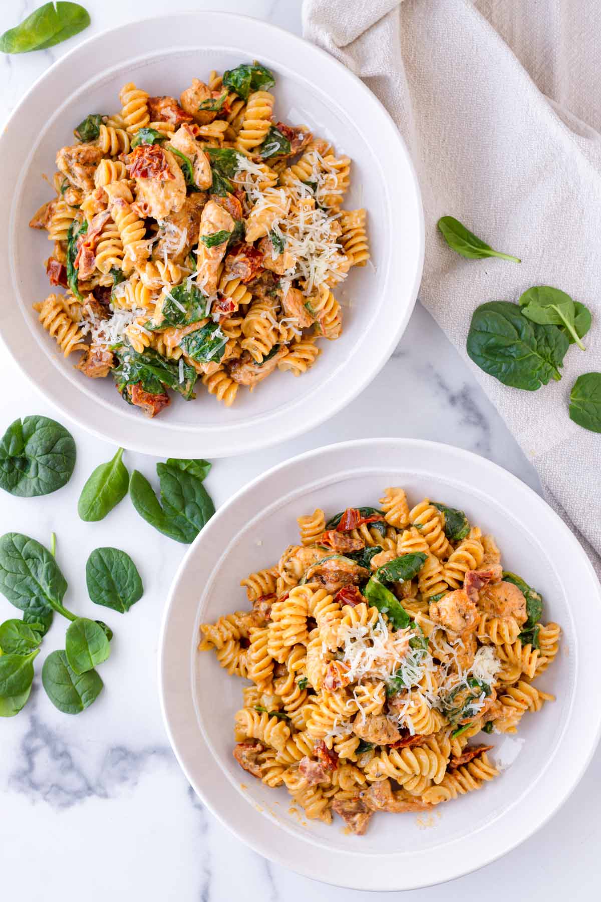 two bowls with tuscan chicken pasta with grated parmesan
