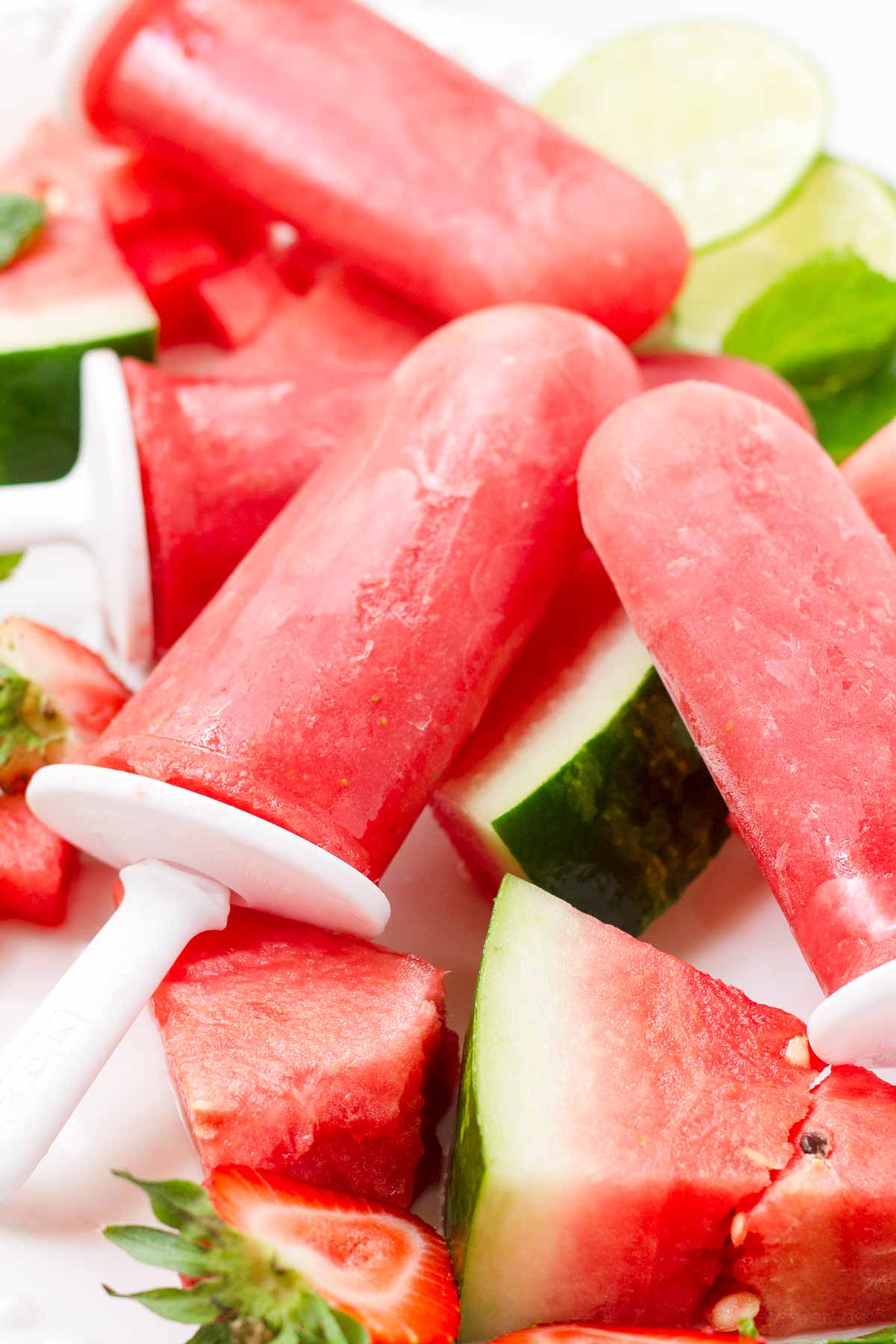 watermelon strawberry popsicles laying on top of a slice of watermelon