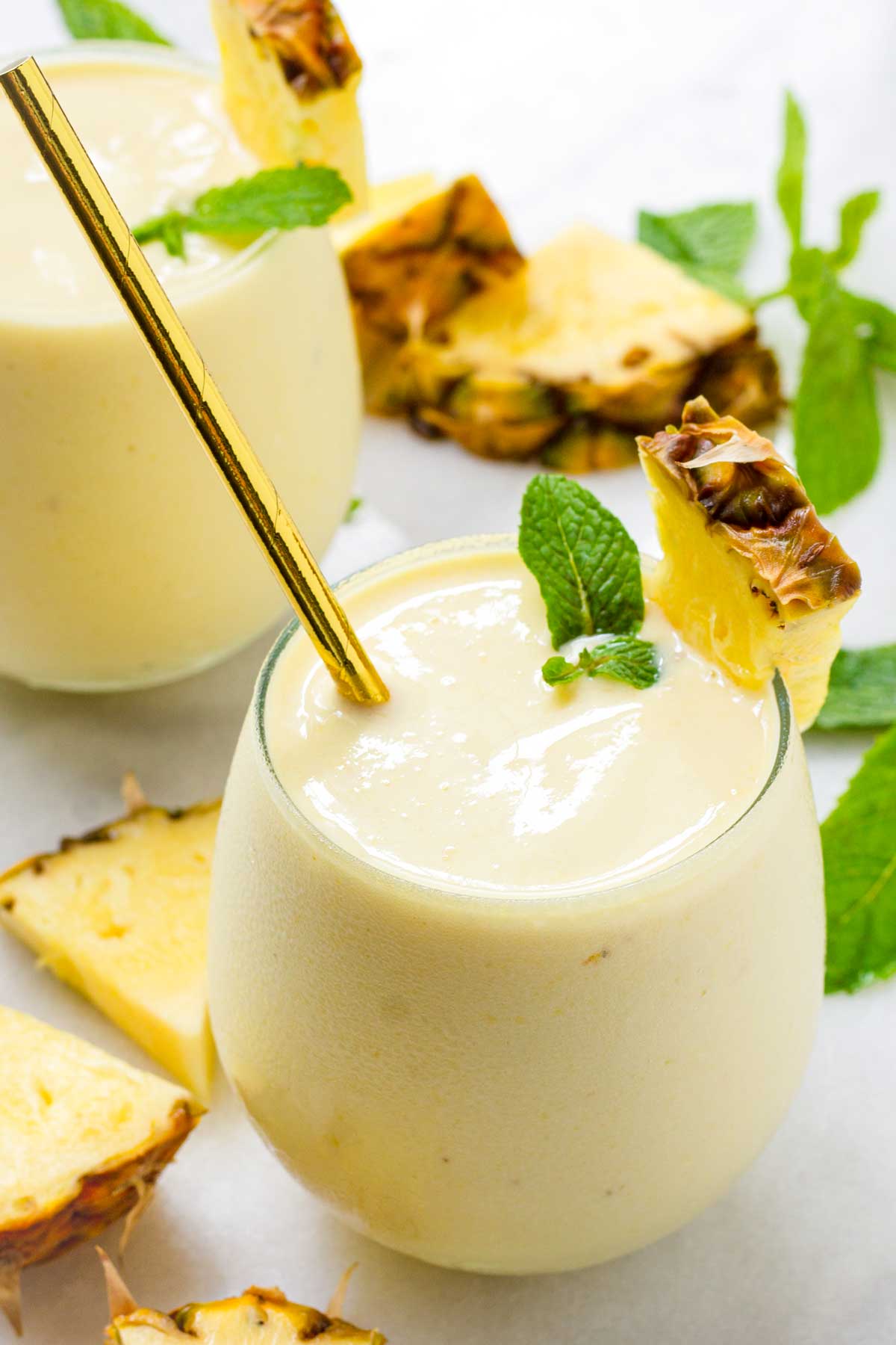 two glasses of pineapple banana smoothies with mint garnish
