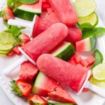 watermelon popsicles on arranged on top of fresh fruit