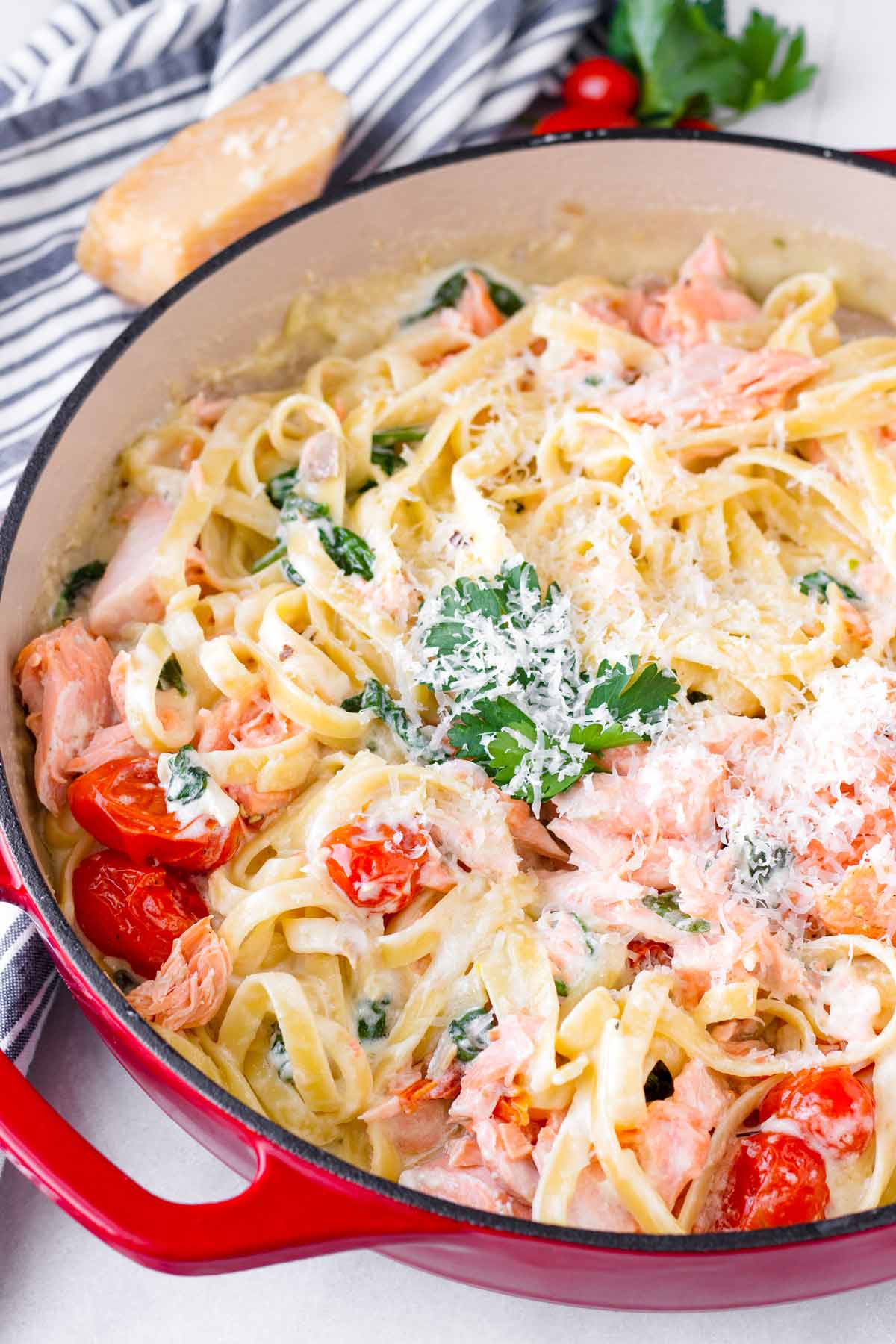 garnished salmon pasta with tomatoes and spinach in a dutch oven