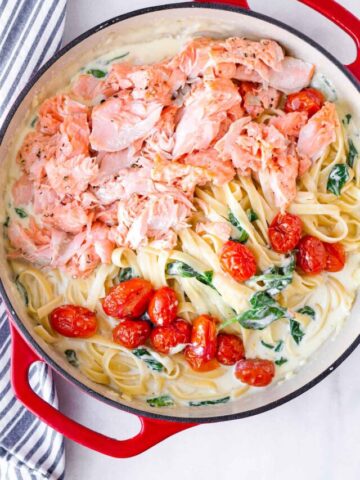 a pot with salmon, roasted tomatoes, spinach, and pasta