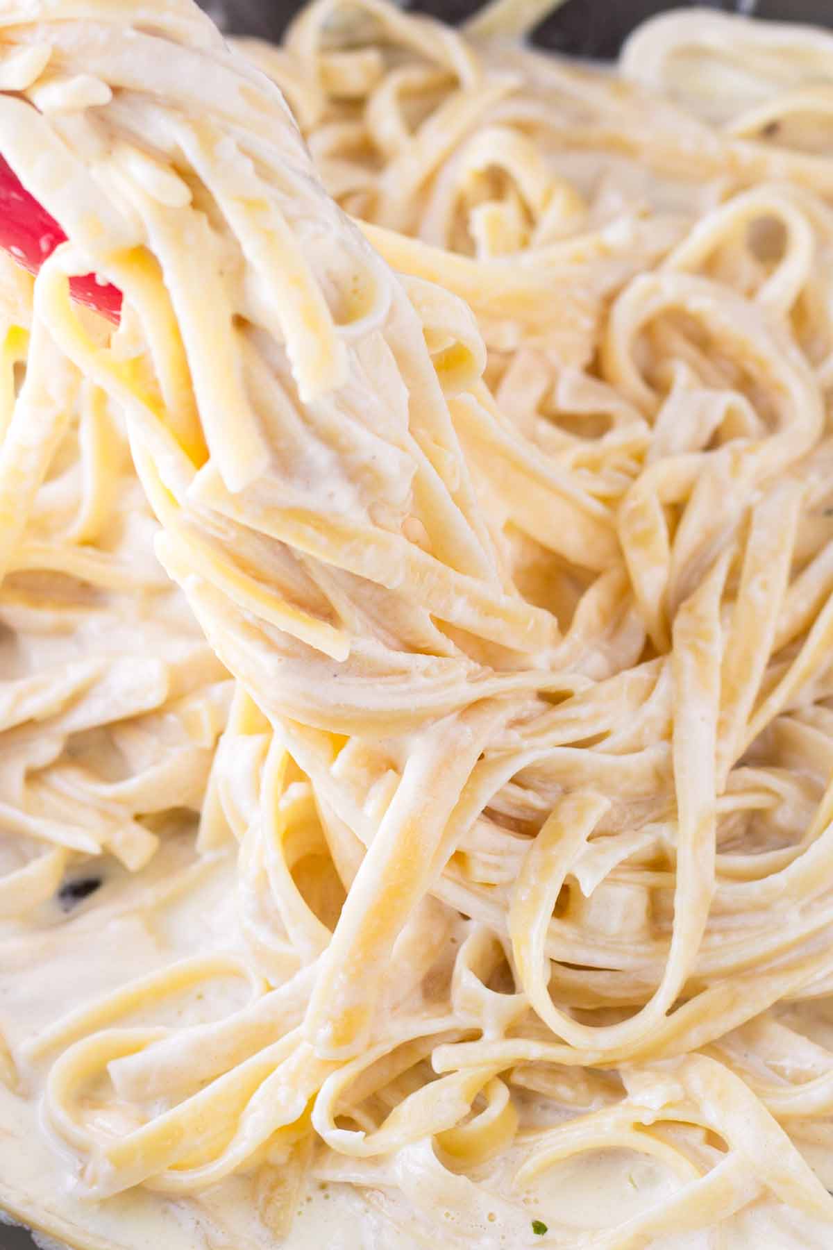 tossing fettuccine with creamy sauce