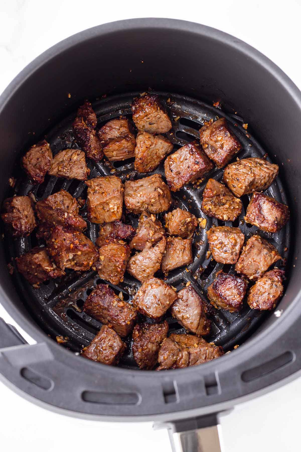 cooked steak bites inside a large air fryer basket
