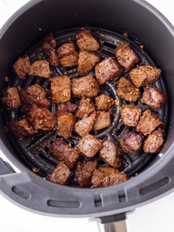 cooked steak bites inside a large air fryer basket