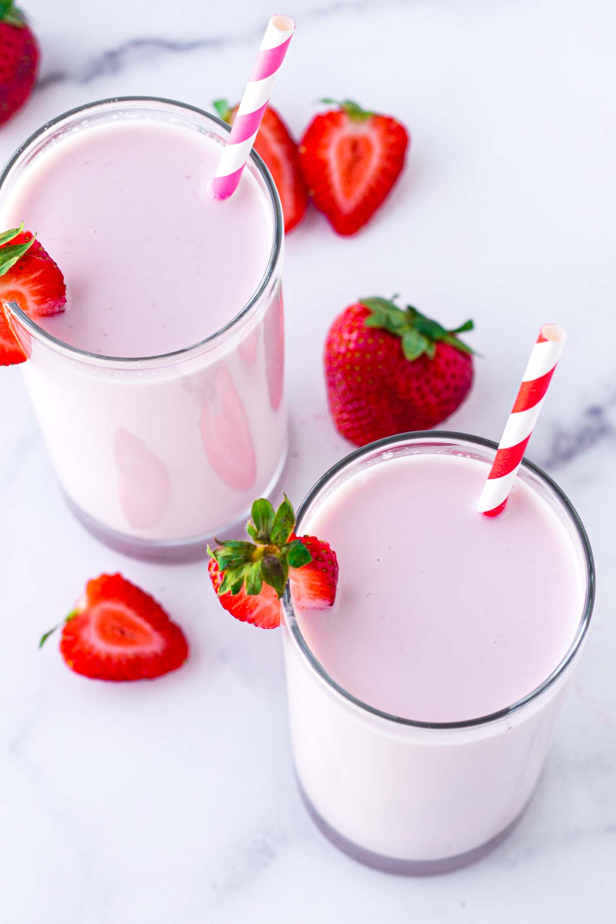 top view of two glasses of strawberry milk with paper straws