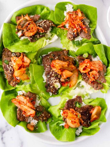 a platter of korean bulgogi lettuce wraps with kimchi topping