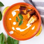 A bowl with tomato bisque served with grilled cheese croutons