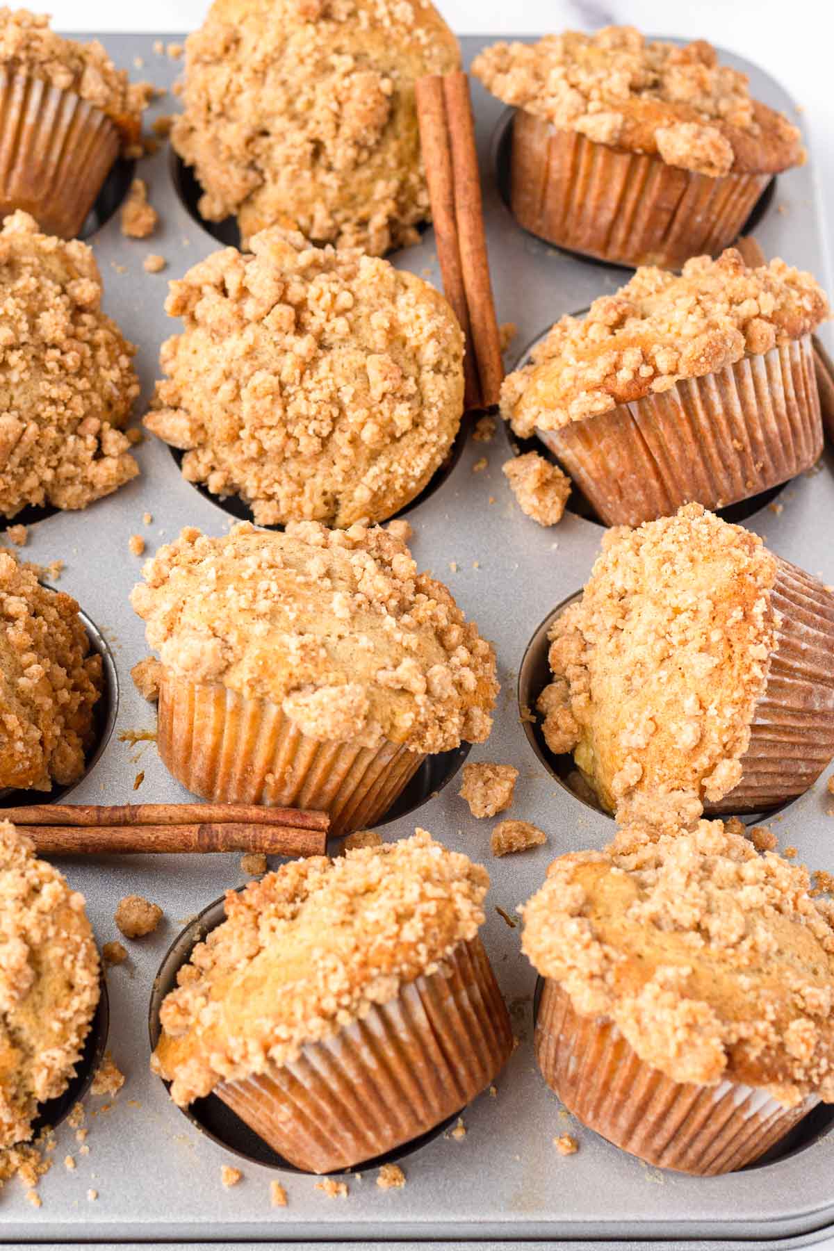 apple cinnamon muffins with crumb topping in a muffin tin