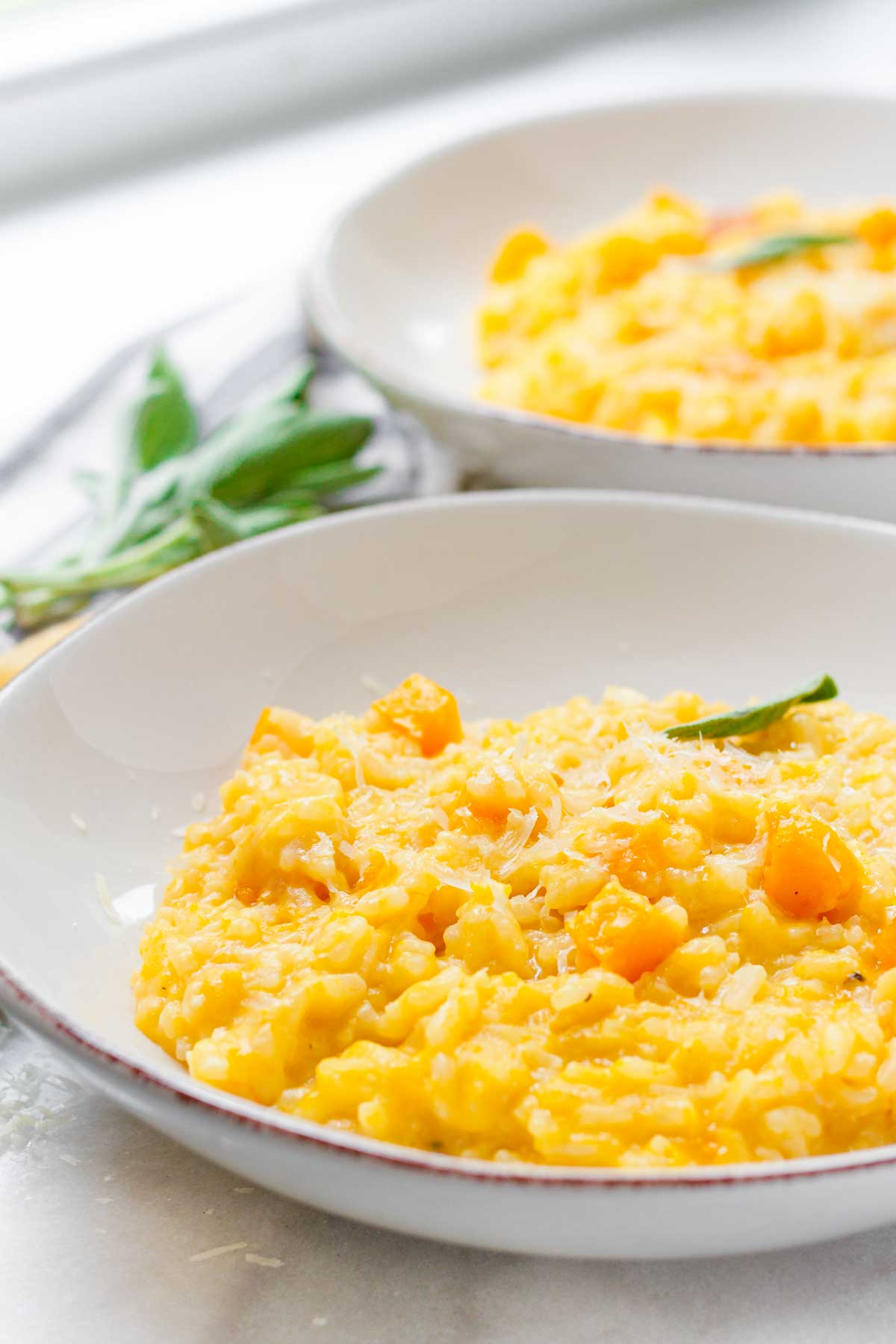 two plates of butternut squash risotto with garnish
