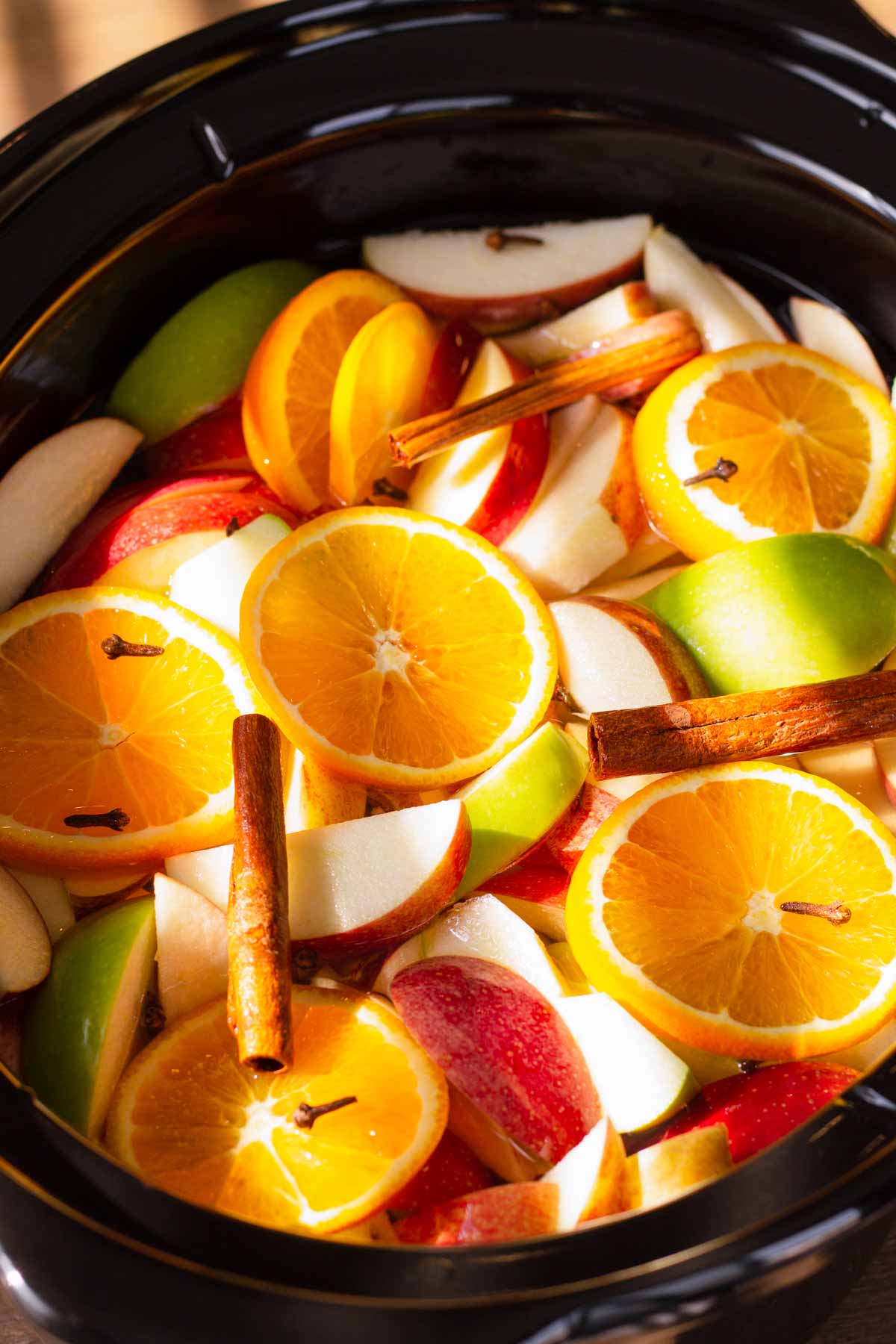 fresh oranges, apples, and cinnamon in a slow cooker
