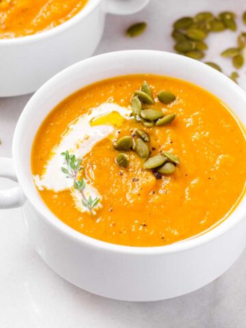 butternut squash soup with pepitas and cream garnish in bowl