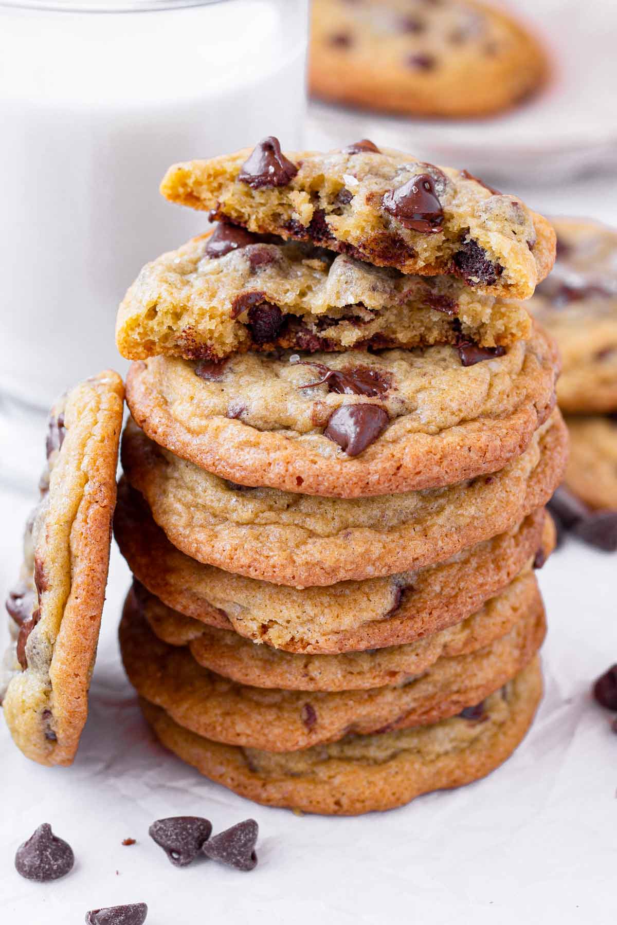 a sea salt chocolate chip cookie split in half sitting on a stack of cookies