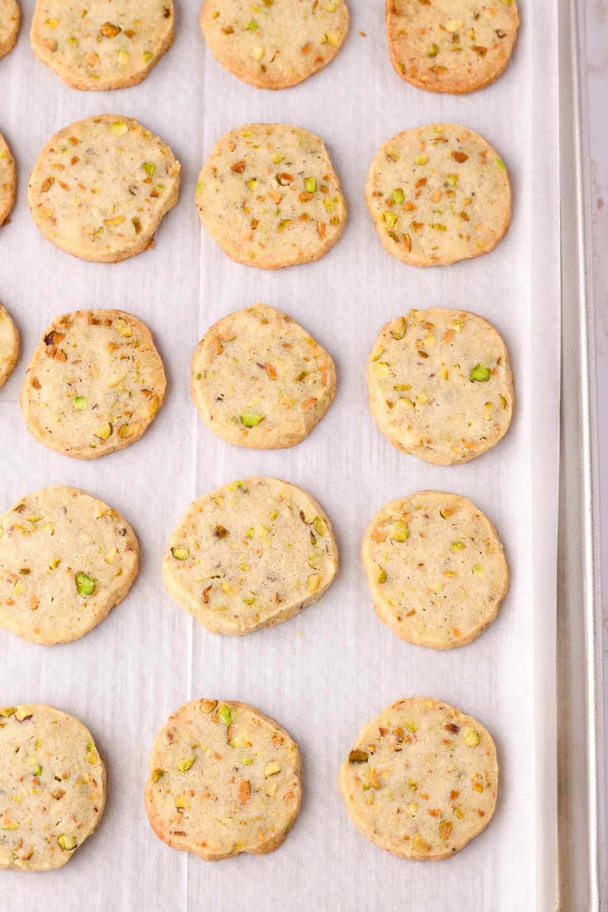 just baked sliced pistachio shortbread cookies on tray