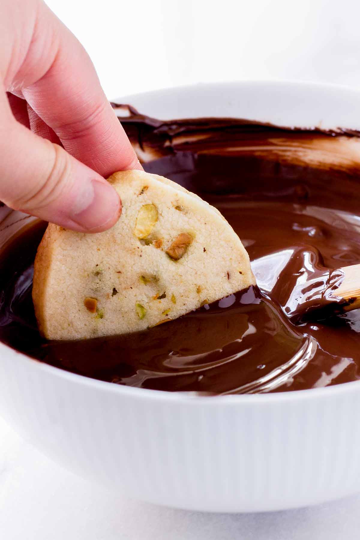 dipping baked cookie into melted chocolate