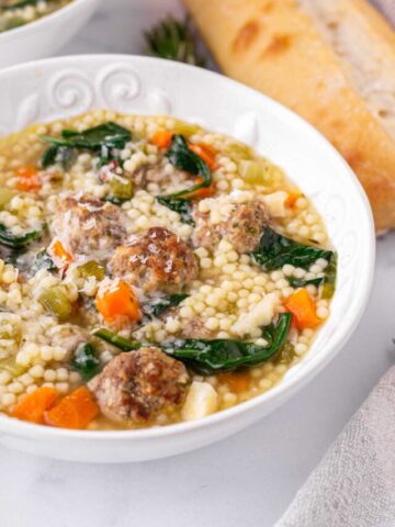 a bowl of italian wedding soup with a side of bread