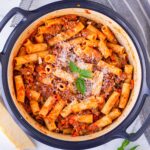 top view of garnished rigatoni alla bolognese in a blue pot