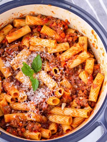 rigatoni with bolognese sauce in a blue dutch oven pot