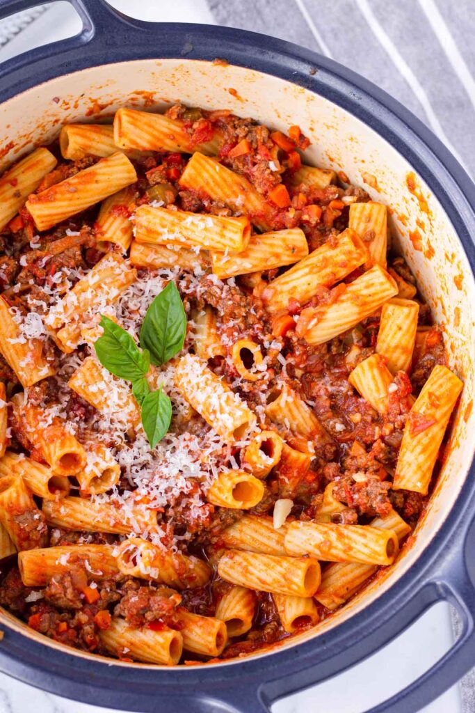 rigatoni with bolognese sauce in a blue dutch oven pot