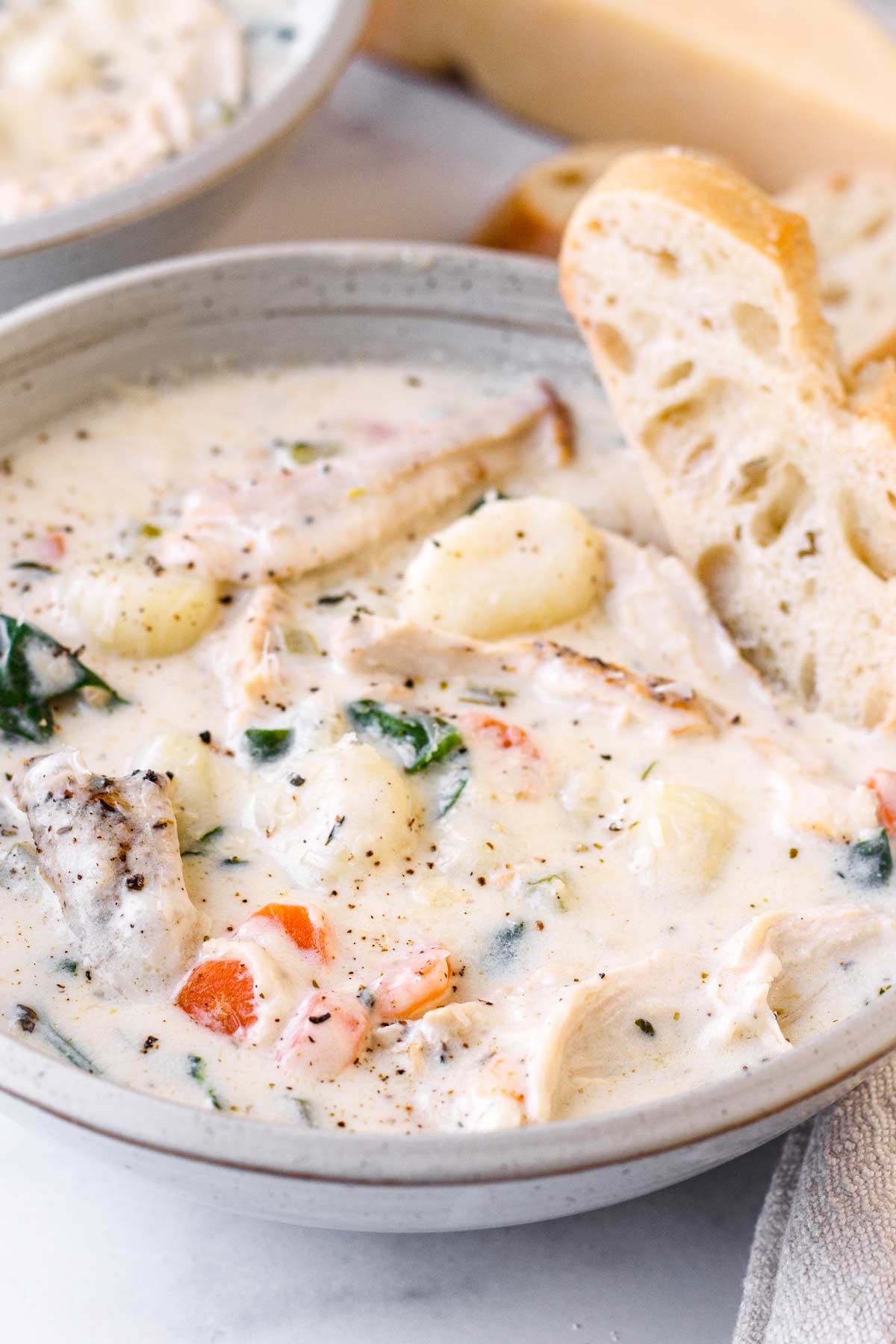 a bowl of chicken gnocchi soup with a slice of bread