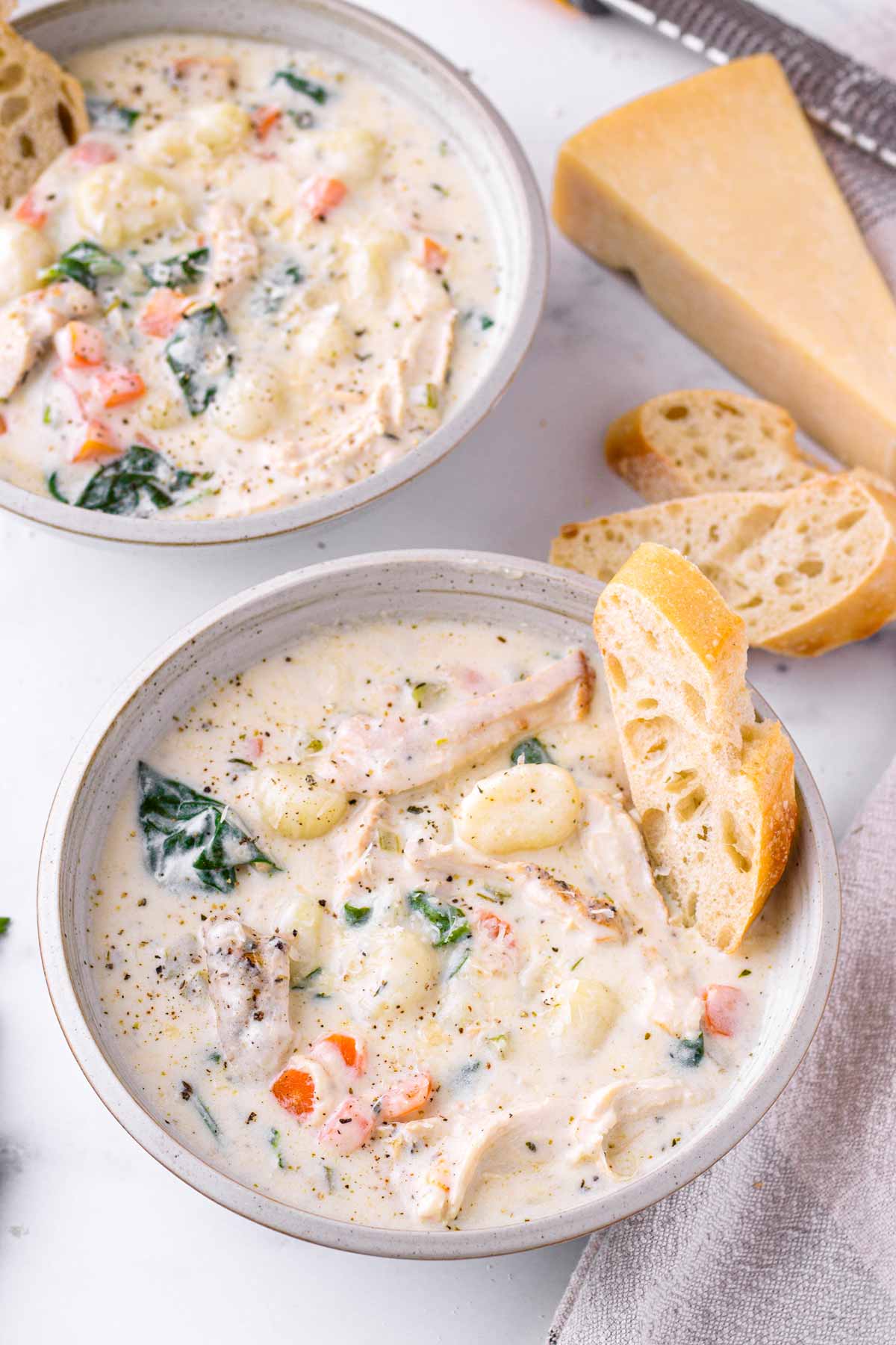 two bowls of creamy soup with gnocchi and chicken