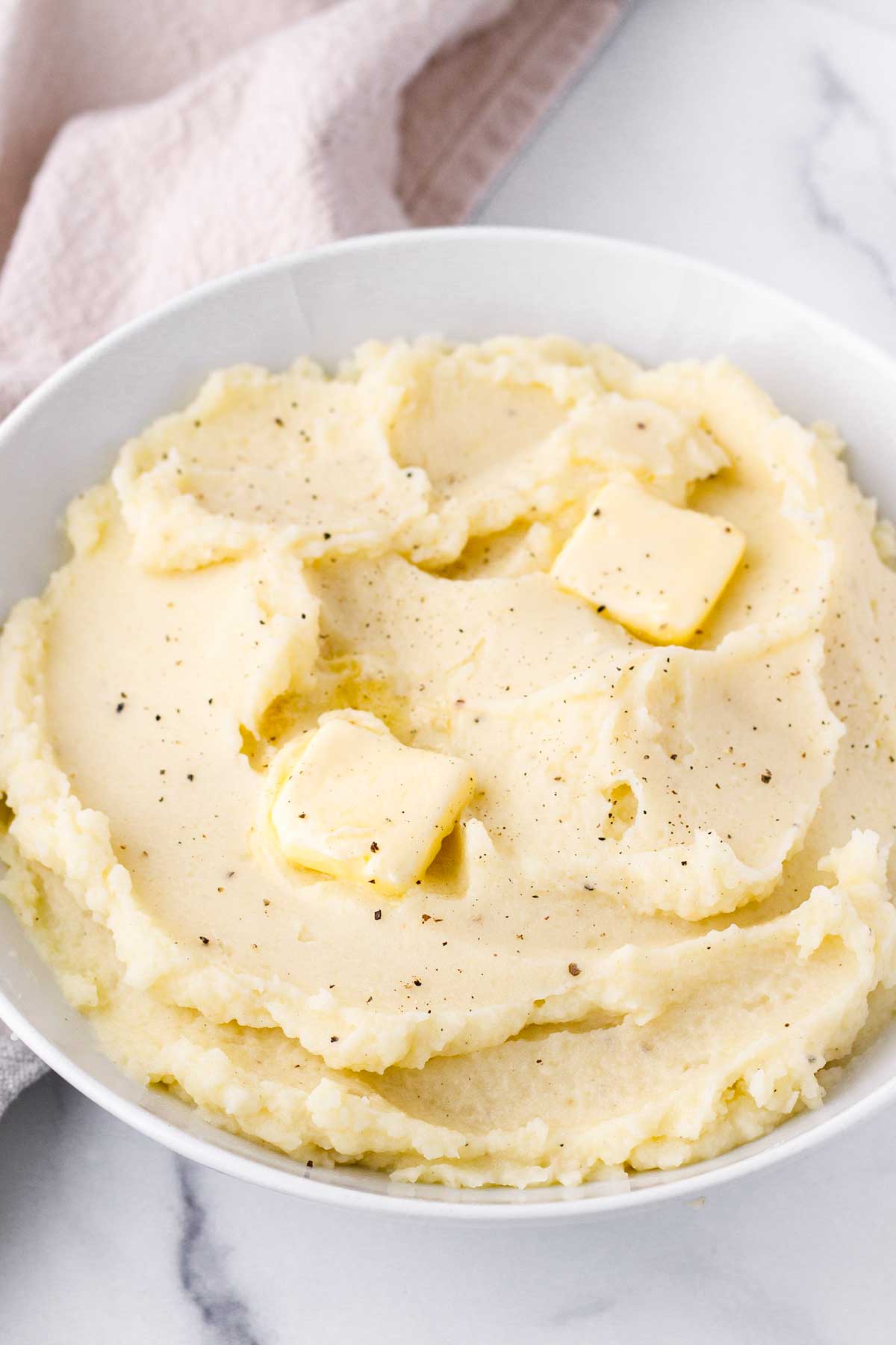 a white porcelain bowl with russet mashed potatoes and butter