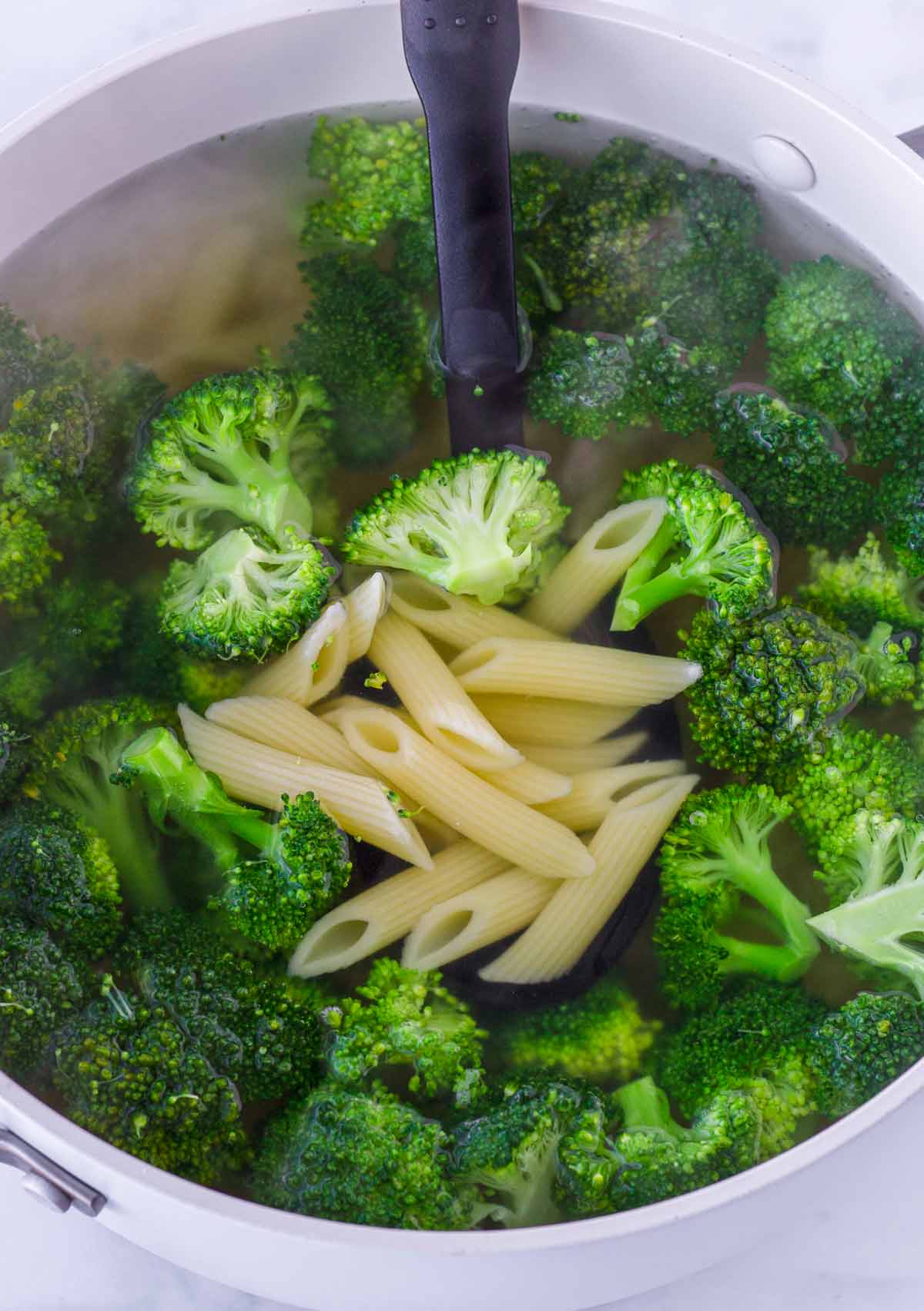 boiling penne and broccoli florets in pot with water