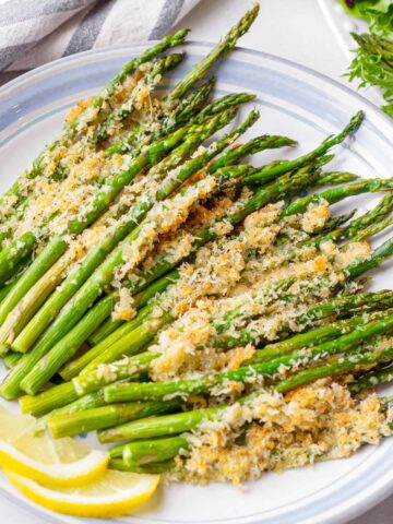 a plate with a roasted asparagus topped with parmesan