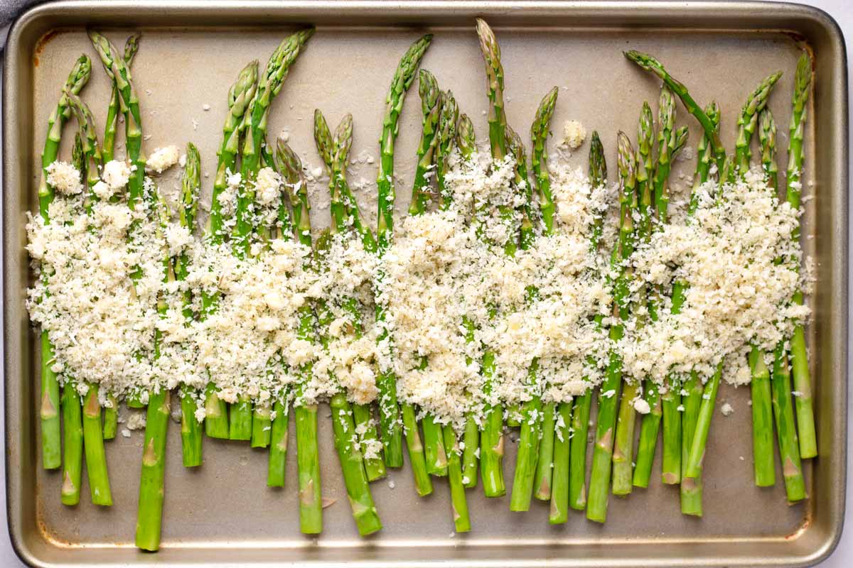 unbaked trimmed asparagus with breading and cheese topping