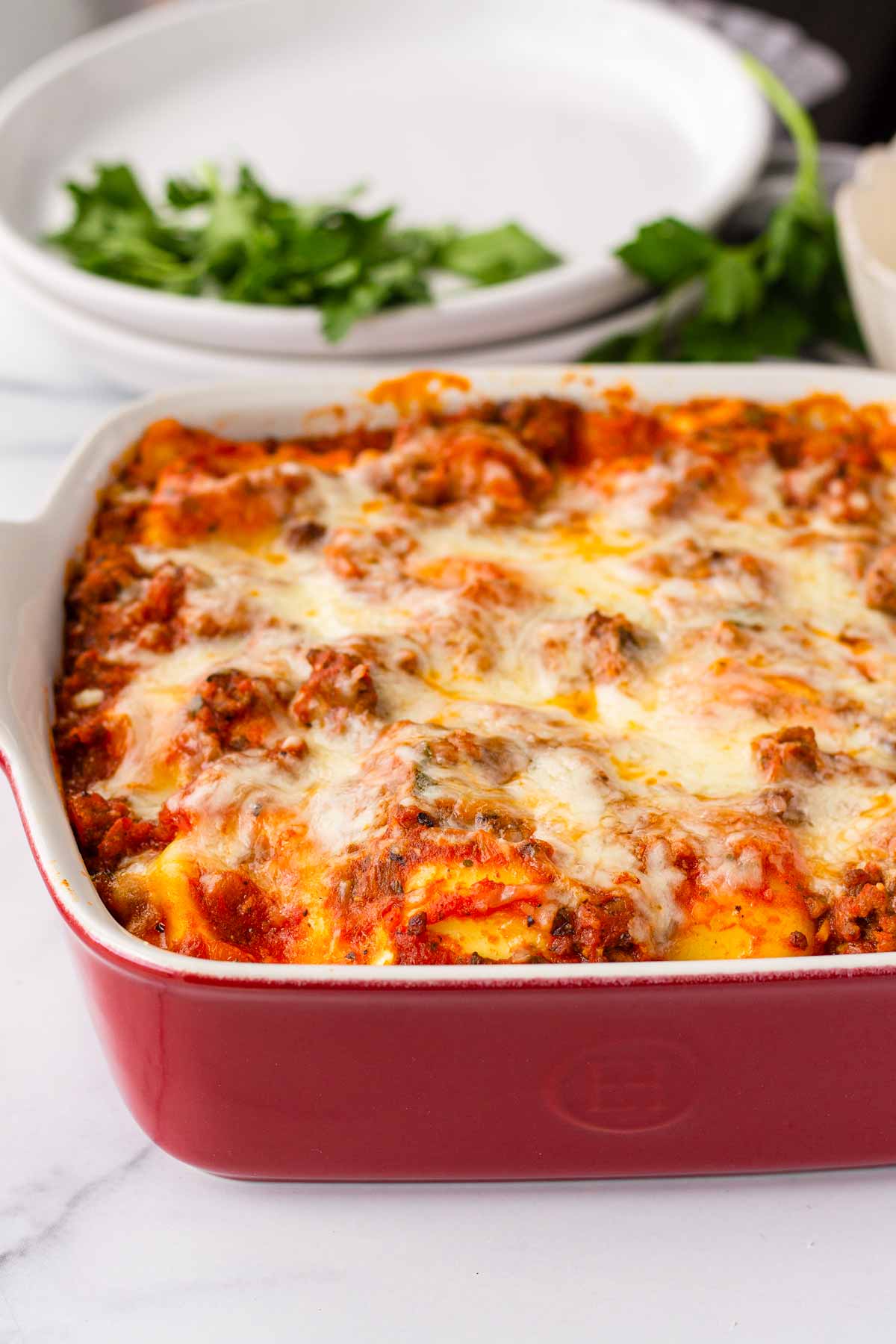 cheesy baked ravioli in a red baking dish
