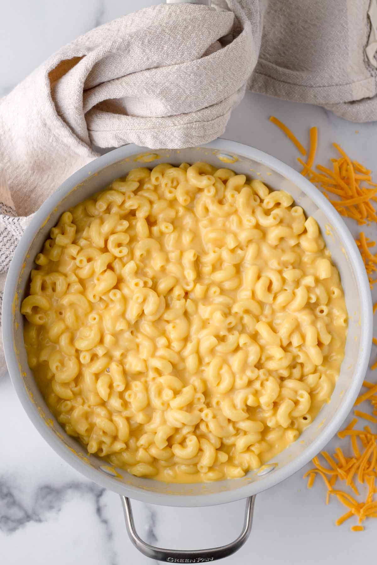 creamy mac and cheese in a pot with towel hanging