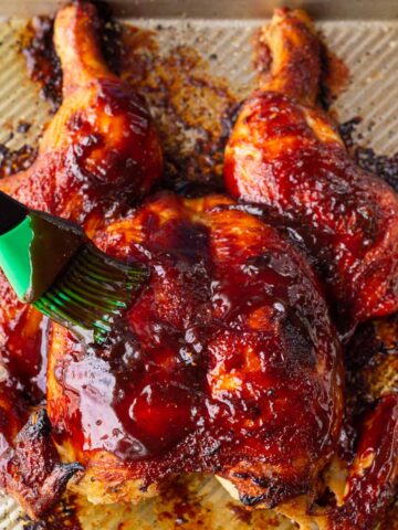 brushing spatchcock chicken with BBQ sauce