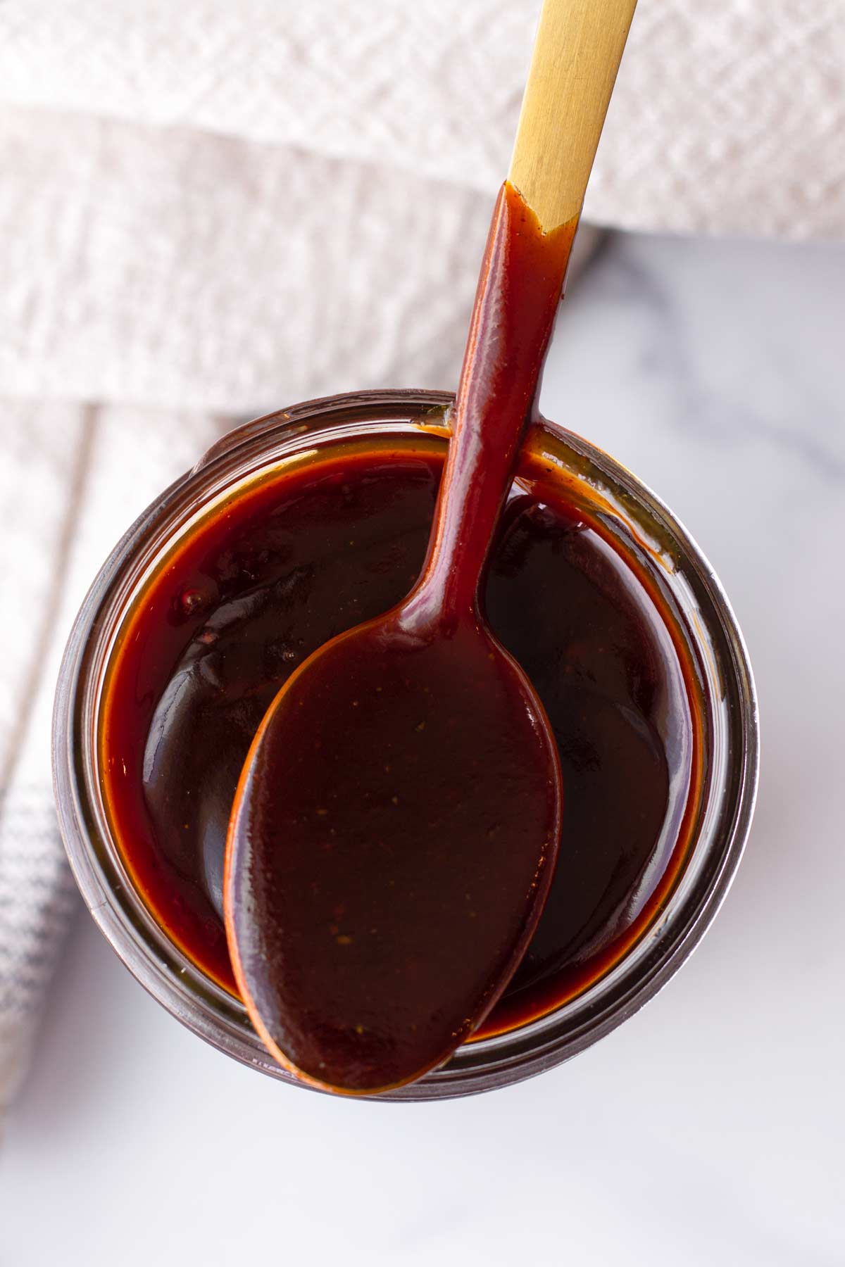 homemade barbecue sauce on a spoon over a container