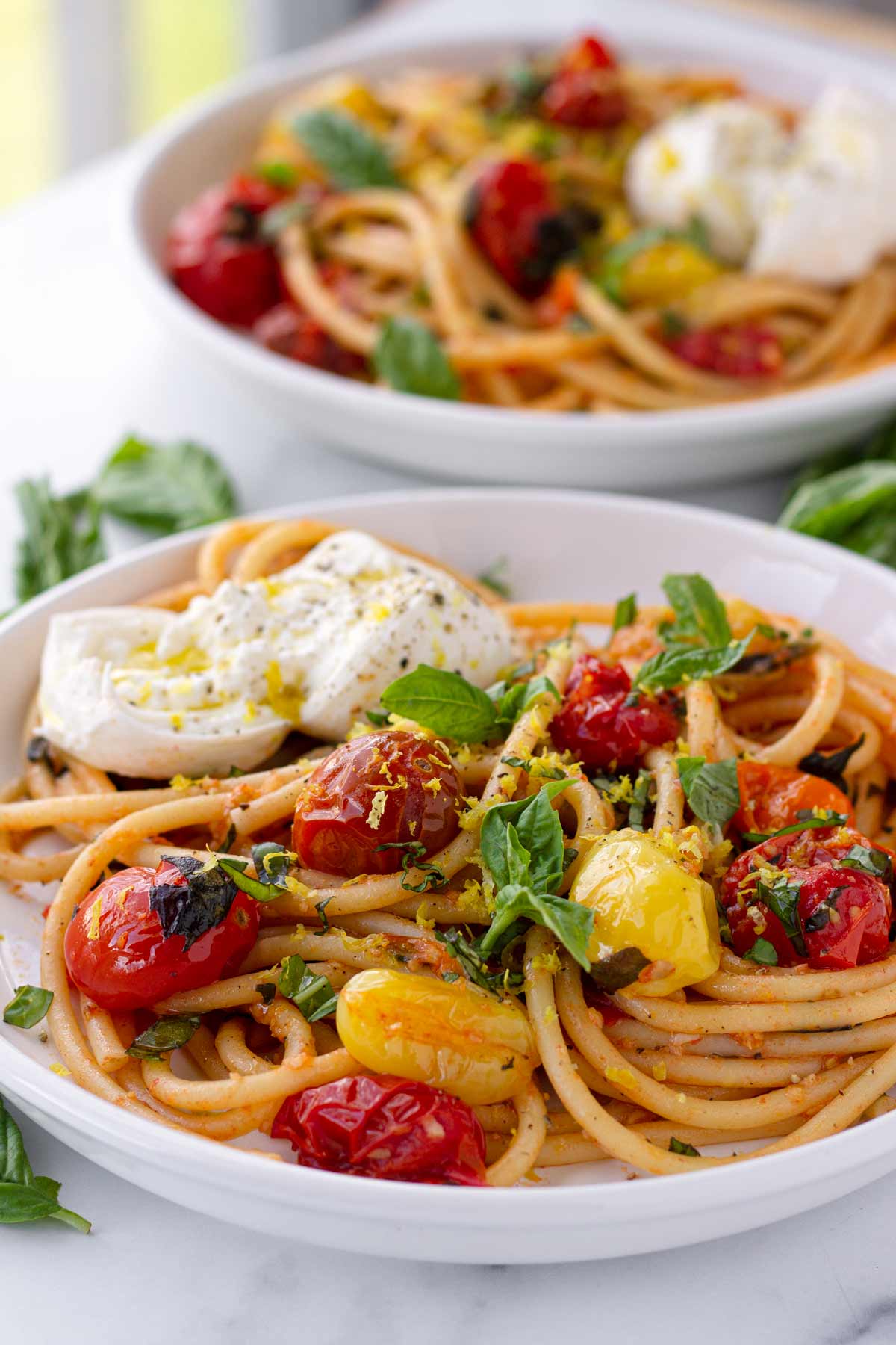 two plates of tomato basil pasta with burrata
