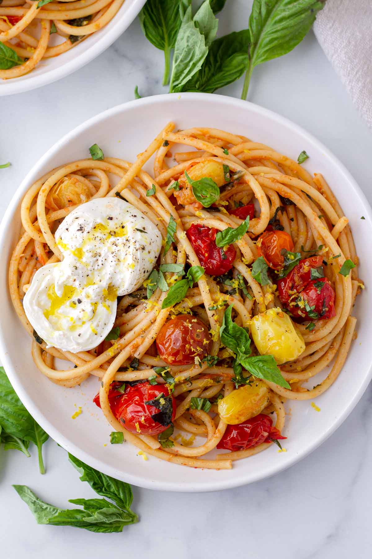 a plate of garnished tomato basil pasta with burrata cheese