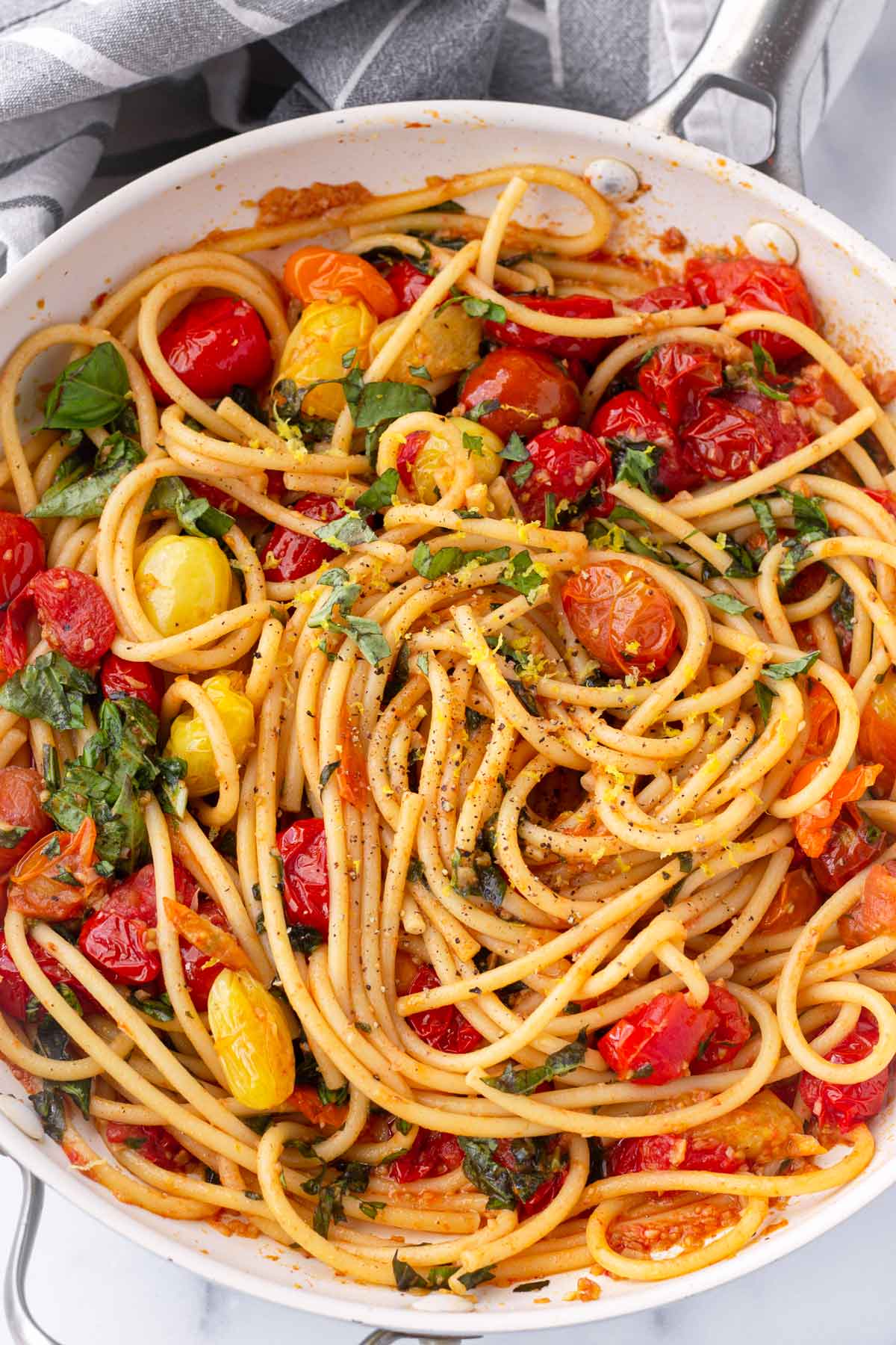 a skillet with finished bucatini with blistered cherry tomato sauce