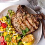 a serving of grilled pork chop with avocado corn salad