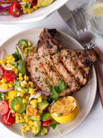 a serving of grilled pork chop with avocado corn salad