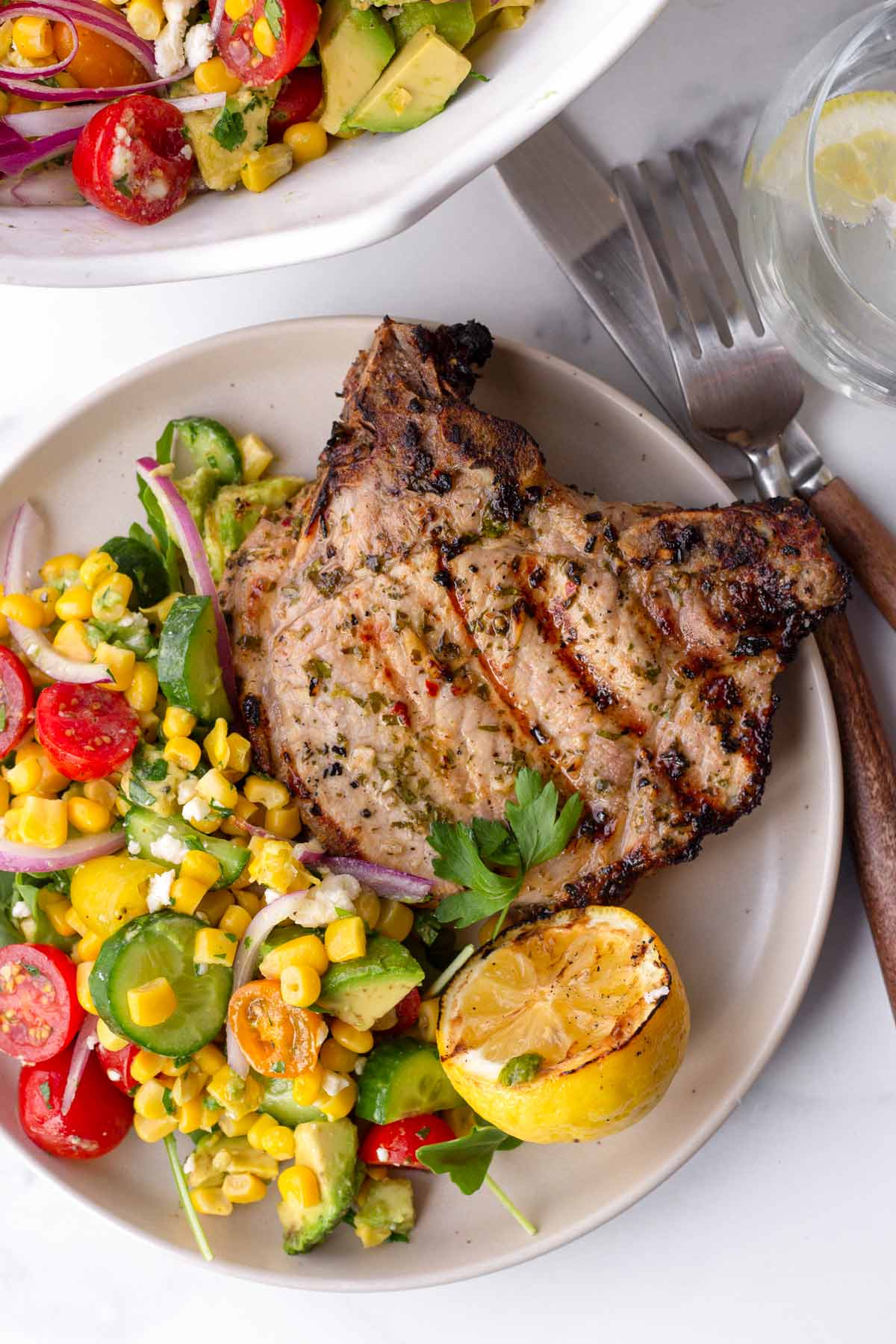 a serving of grilled pork chop with avocado corn salad