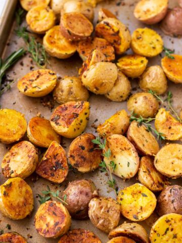 a sheet pan with herb roasted potatoes and herbs garnish