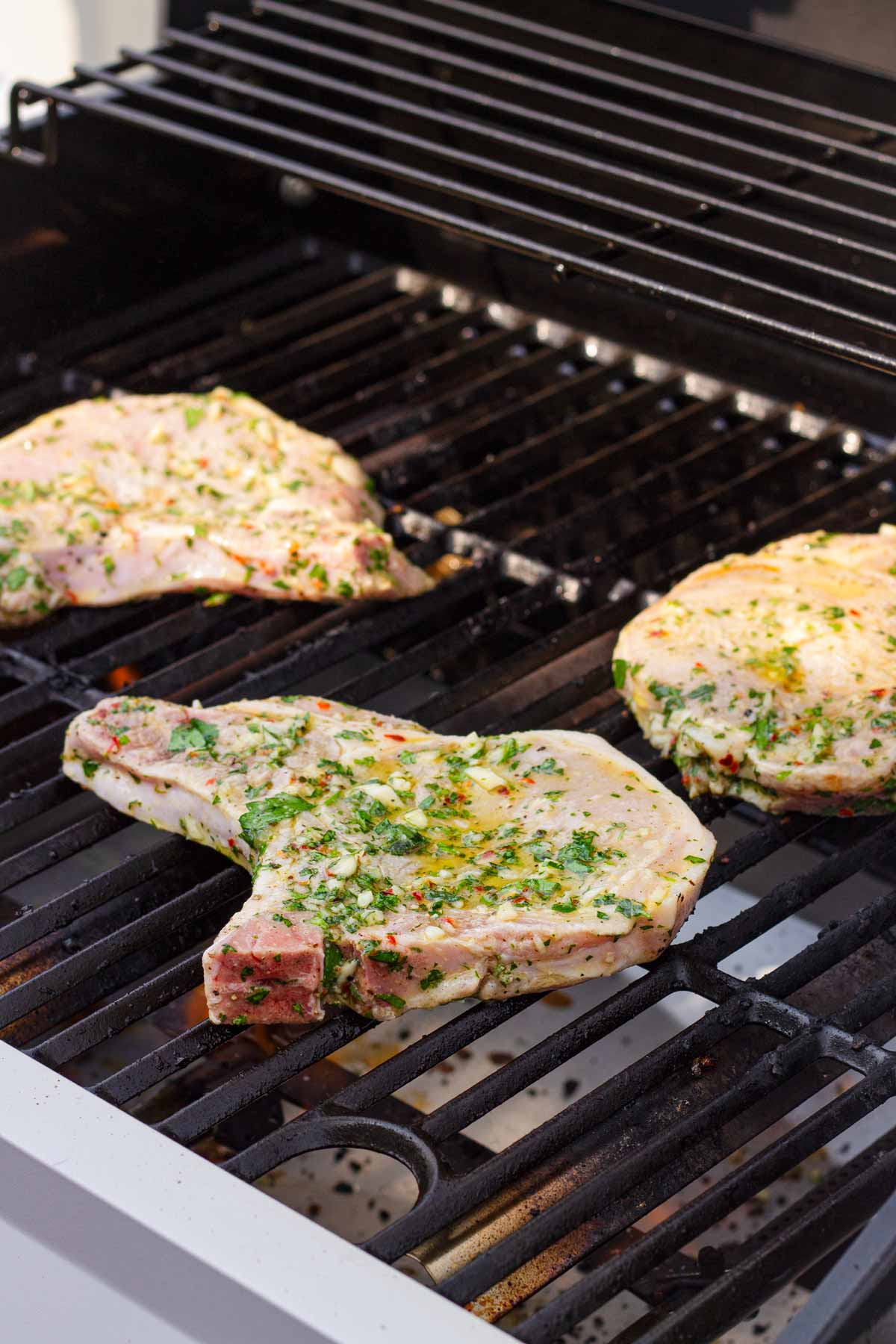 grilling three pork chops on a grill outdoors