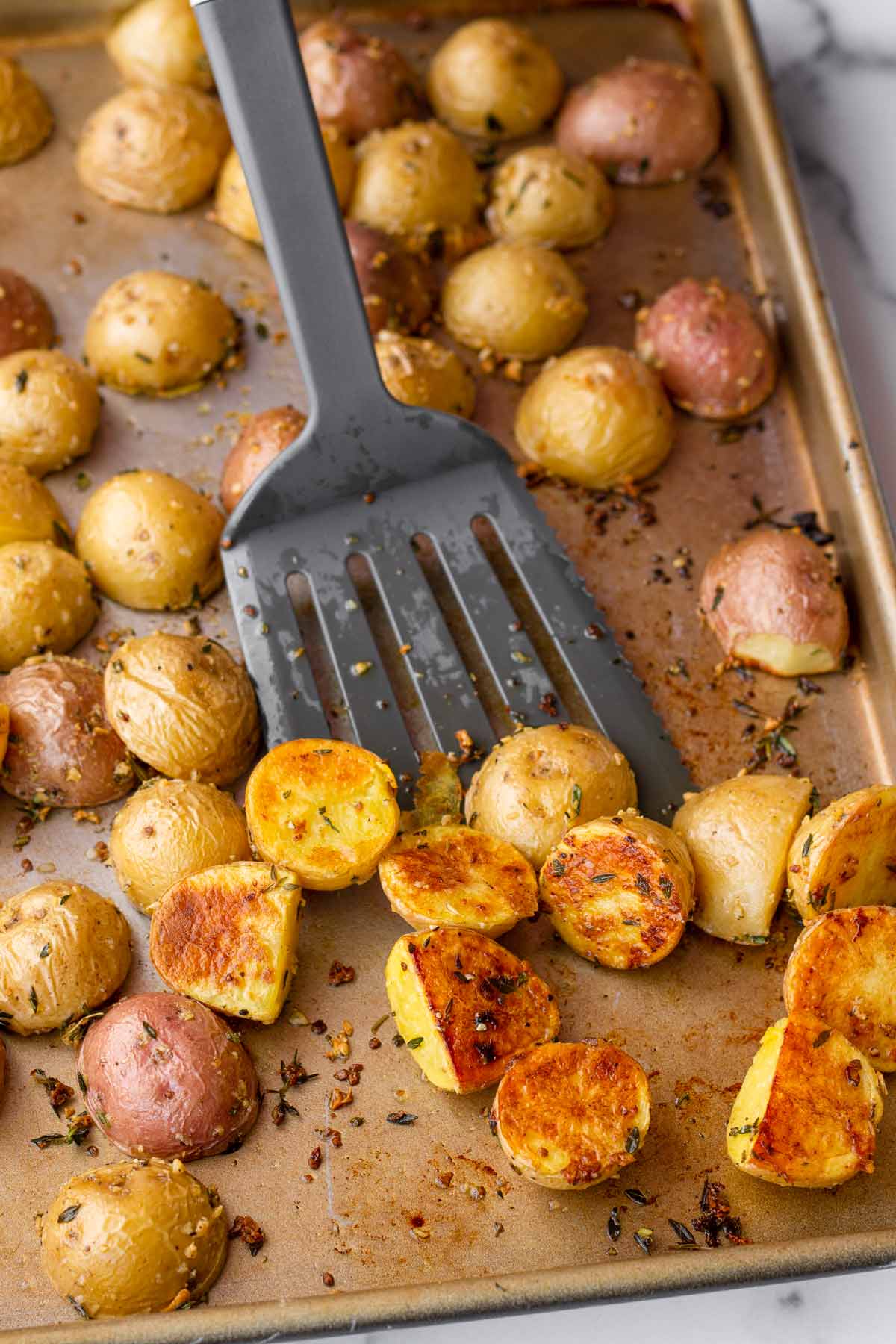 flipping the potatoes on sheet pan with spatula