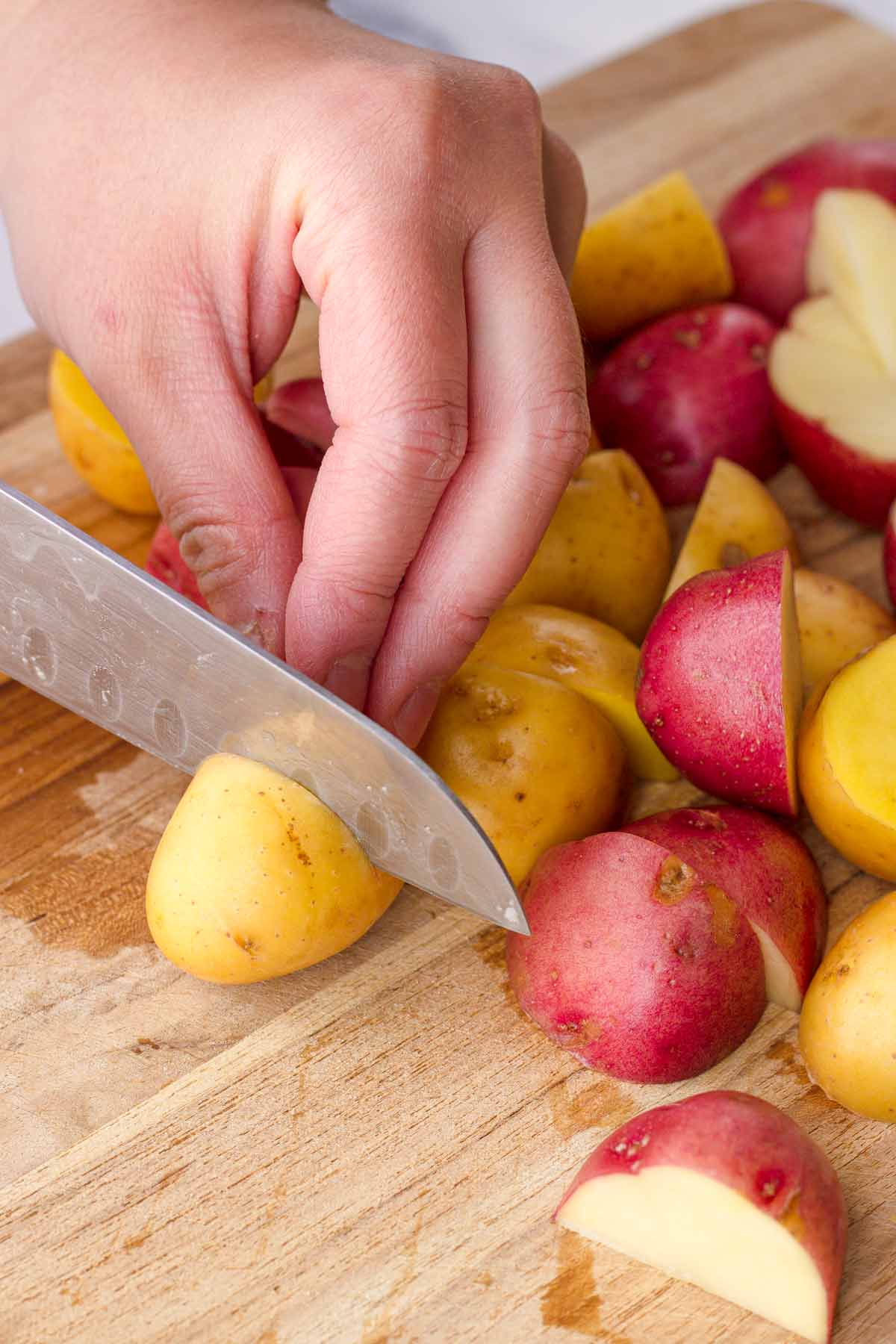 cutting potatoes into half on cutting board