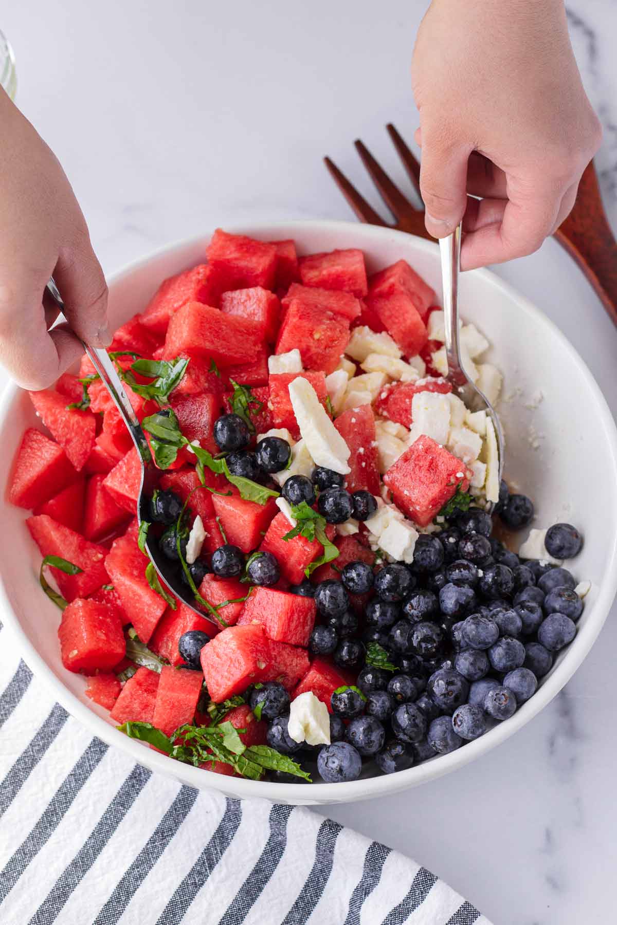 mixing all the ingredients of watermelon salad in a bowl